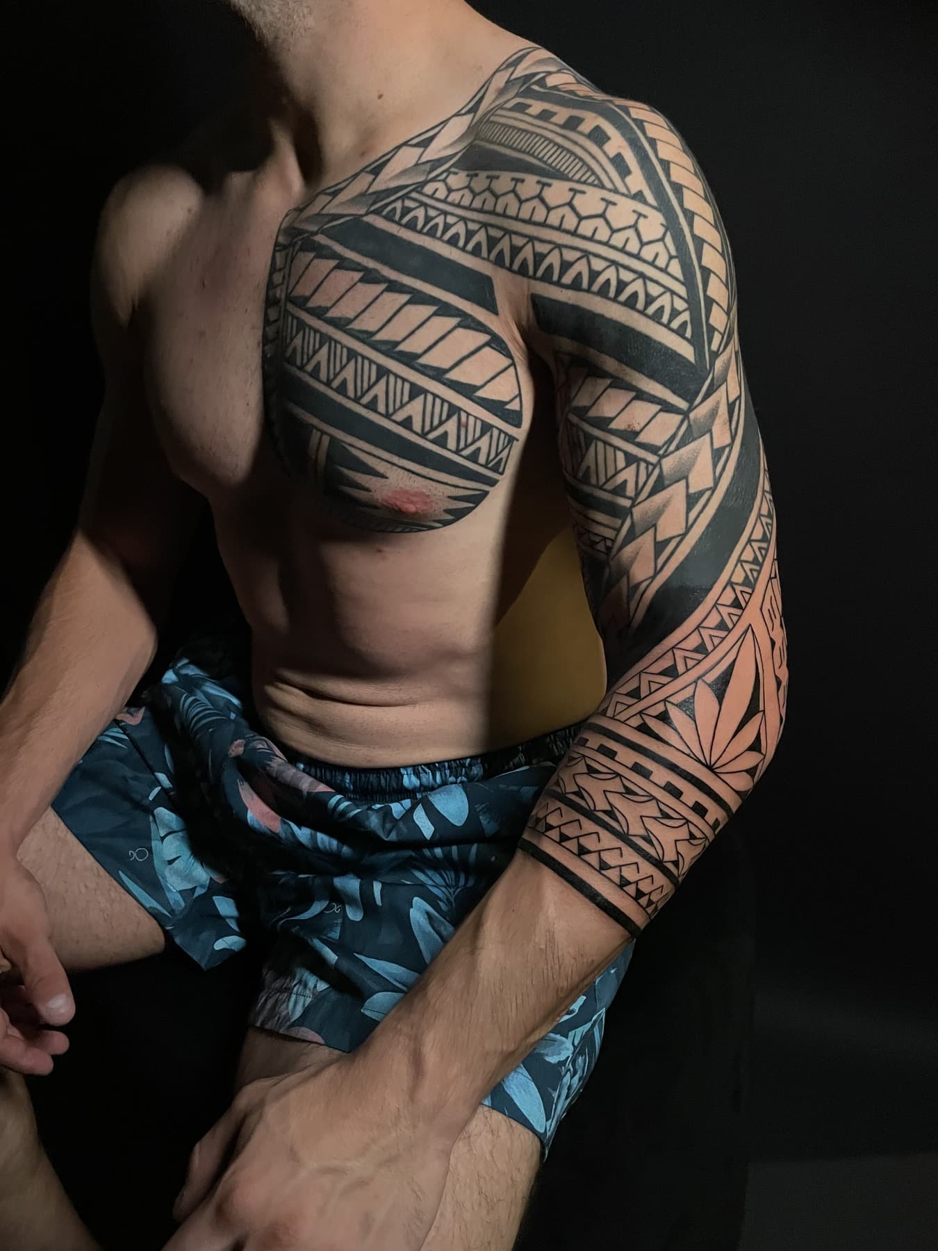 Peito e manga fechada em tribal polinésio, com preenchimento sólido e padrões em faixas.