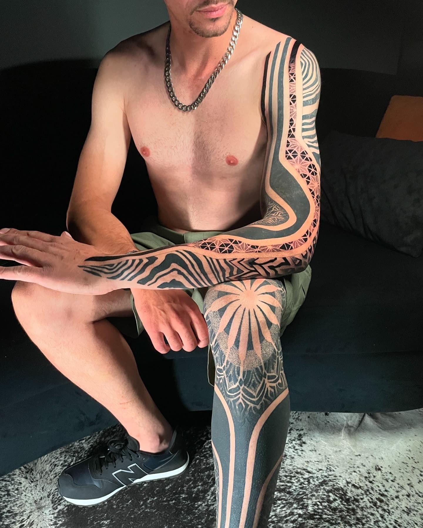 Braço e perna fechados em blackwork: listras ópticas, mandala em pontilhismo e preto sólido.